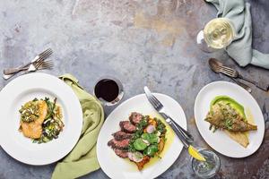 Big dinner table overhead view with steak and fish photo