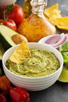 Guacamole in white bowl with lime and hot pepper photo