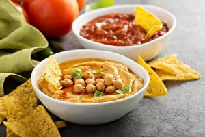 Homemade hummus and tomato salsa in white bowls with chips photo