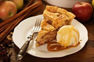 Piece of an apple pie with ice cream on a plate photo