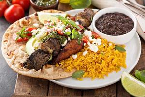 Beef kebab with rice, beans and fried plantains photo