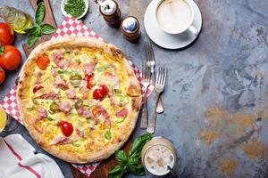 pizza de desayuno con huevos revueltos, jamón y tomates foto