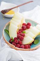 Melon slices served with raspberry and honey photo