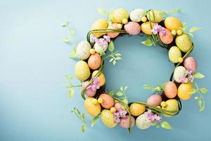 Easter eggs wreath on light blue background photo