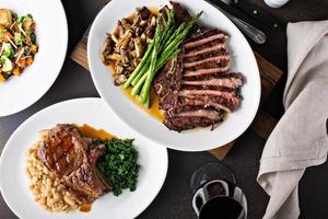 Overhead shot of a dinner table with steak and grilled pork photo