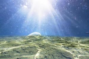 desenfoque azul transparente borroso bajo la textura de la superficie del agua con salpicaduras y burbujas. fondo de naturaleza abstracta de moda. olas del océano a la luz del sol con espacio de copia. azul bajo el mar acuarela brillante foto