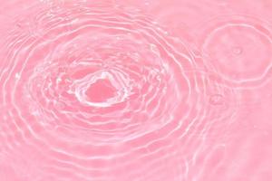 Defocus blurred transparent purple colored clear calm water surface texture with splashes and bubbles. Trendy abstract nature background. Water waves in sunlight with copy space. Pink water drop shine photo