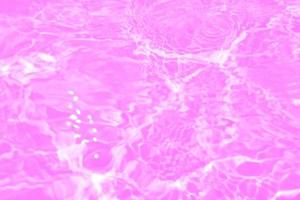 Defocus blurred transparent purple colored clear calm water surface texture with splashes and bubbles. Trendy abstract nature background. Water waves in sunlight with copy space. Pink water drop shine photo