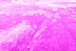 Defocus blurred transparent purple colored clear calm water surface texture with splashes and bubbles. Trendy abstract nature background. Water waves in sunlight with copy space. Pink water drop shine photo