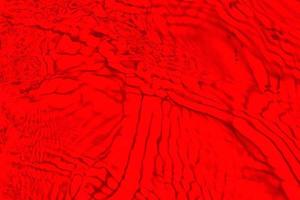 desenfoque borrosa transparente color rojo claro agua tranquila textura superficial con salpicaduras y burbujas. fondo de naturaleza abstracta de moda. ondas de agua a la luz del sol con espacio de copia. acuarela roja brillante foto