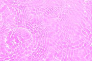 Defocus blurred transparent purple colored clear calm water surface texture with splashes and bubbles. Trendy abstract nature background. Water waves in sunlight with copy space. Pink water drop shine photo