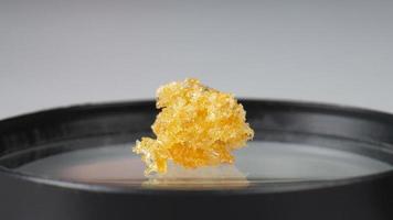 golden crystals of cannabis wax, glass container with crumbs of marijuana concentrate and copy space photo