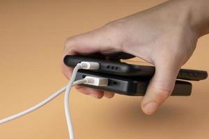 connecting usb portable power bank accumulator and phone black color in hand photo