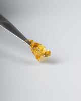 cannabis wax dab concentrate on a stick for smoking essential oils on white background closeup photo