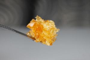 Concentrado de cera de cannabis amarillo ámbar que gotea del primer plano de la herramienta dabbing foto