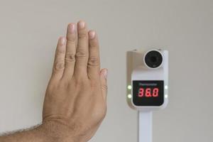 Raise your hand to take body temperature near a thermometer to prevent covid19 photo