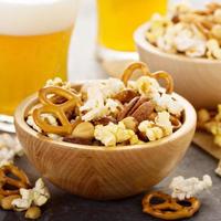 Homemade trail or snack mix with popcorn, pretzels and nuts with beer