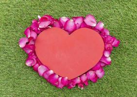 Top view pink rose petals arranged in a heart shape with mock up red heart in the middle. Valentine day concept. photo