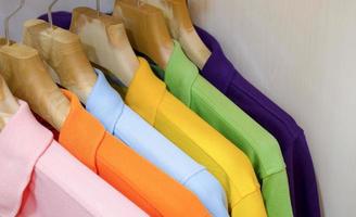 Many colorful shirts hanging on a rack photo