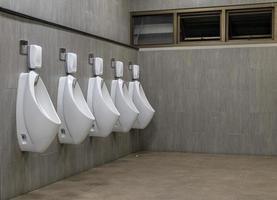 Men's room with white porcelain urinals in line photo