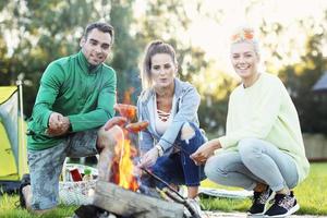 Group of friends preparing marshmallow on campfire photo