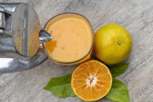 Orange juice in glass and fresh citrus around with Juicer hand press squeezer fruit on wood table photo