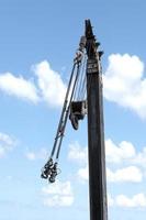 Yellow crane boom with hooks and blue sky background photo