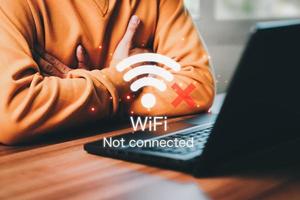 hombre usando una computadora portátil para conectarse a wifi pero wifi no conectado, y esperando para cargar el sitio web del formulario de datos comerciales digitales, tecnología conceptual de espera para conectarse a wifi. foto