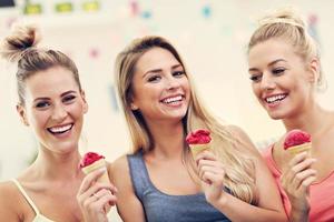 Three beautiful young women eating ice-cream at home photo