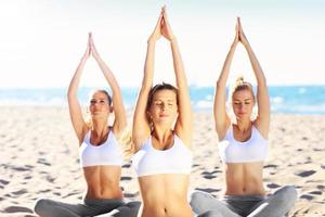 grupo de mujeres practicando yoga en la playa foto