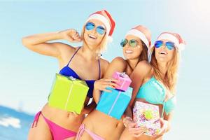 grupo de chicas con sombreros de santa divirtiéndose en la playa foto