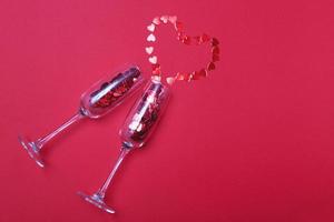 Glass of champagne with red hearts on red background. Valentines background, love, date concept with copy space photo