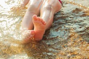 kids feet on the beach in the water photo