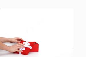 hands of a young man holding a present box with red hearts on a white background photo