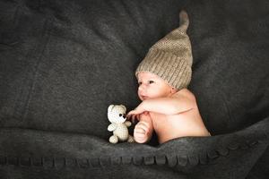 newborn baby with a toy lying next to the knitted teddy bear photo