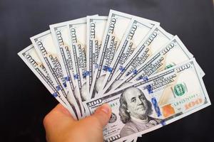 Hand with dollar bills on a black background photo