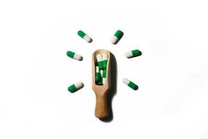 medicine green pills on white background on a wooden spoon in the form of a light bulb . Copy space for text. photo