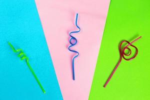 Disposable curly plastic multicolored tubules for drinks on multicolored background, copy space. Festive concept photo