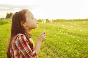 girl blows on a dandelion photo