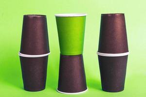 Eco-friendly disposable brown and green paper cups on green background. Ecology concept. photo