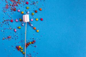 marshmallows composition on wooden skewers on blue background. Flat lay, holiday concept. flower-shaped sweets photo