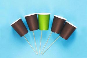 Eco-friendly disposable brown and green paper cups on blue background. Ecology concept. photo