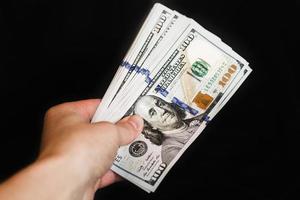 Hand with dollar bills on a black background photo