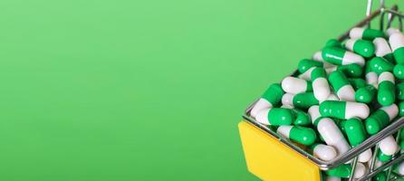 Shopping cart with medical pills on a green background. banner photo