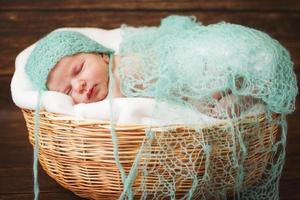 Newborn baby sleeping on a wooden background in the Wicker basket photo