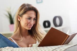 Happy woman reading on sofa photo