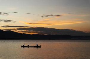 two fishermen on the lake from a boat at sunset. Limboto Lake, Gorontalo, Indonesia. beautiful sky in the afternoon photo