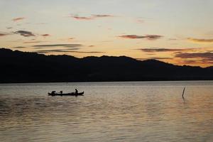 two fishermen on the lake from a boat at sunset. Limboto Lake, Gorontalo, Indonesia. beautiful sky in the afternoon photo