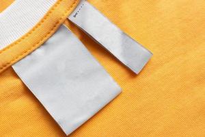 Blank white laundry care clothes label on yellow fabric texture background photo