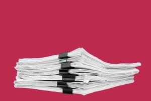 A stack of papers with paper clips, office folders on a carmine red background. photo